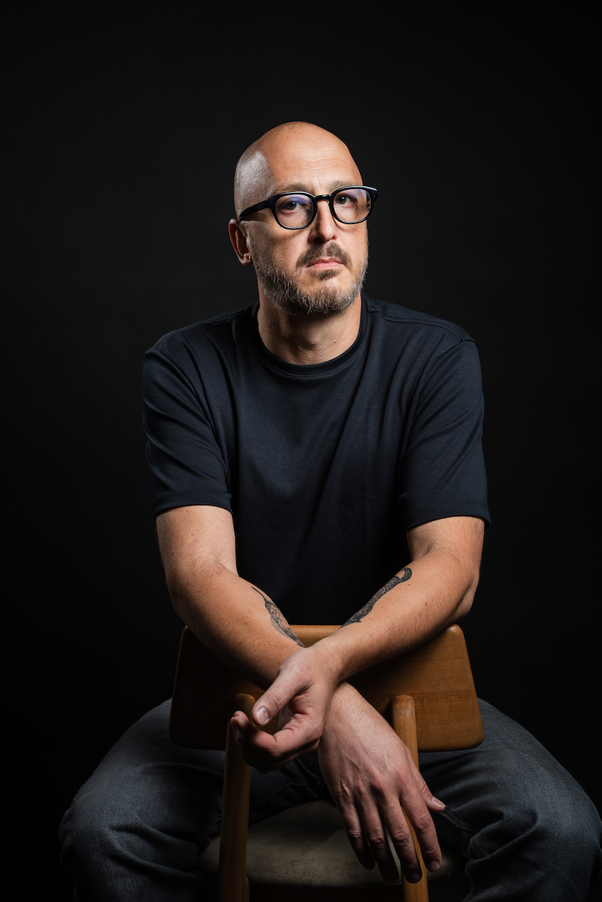 Portrait of Andre R. Cunha seated, against a dark background.